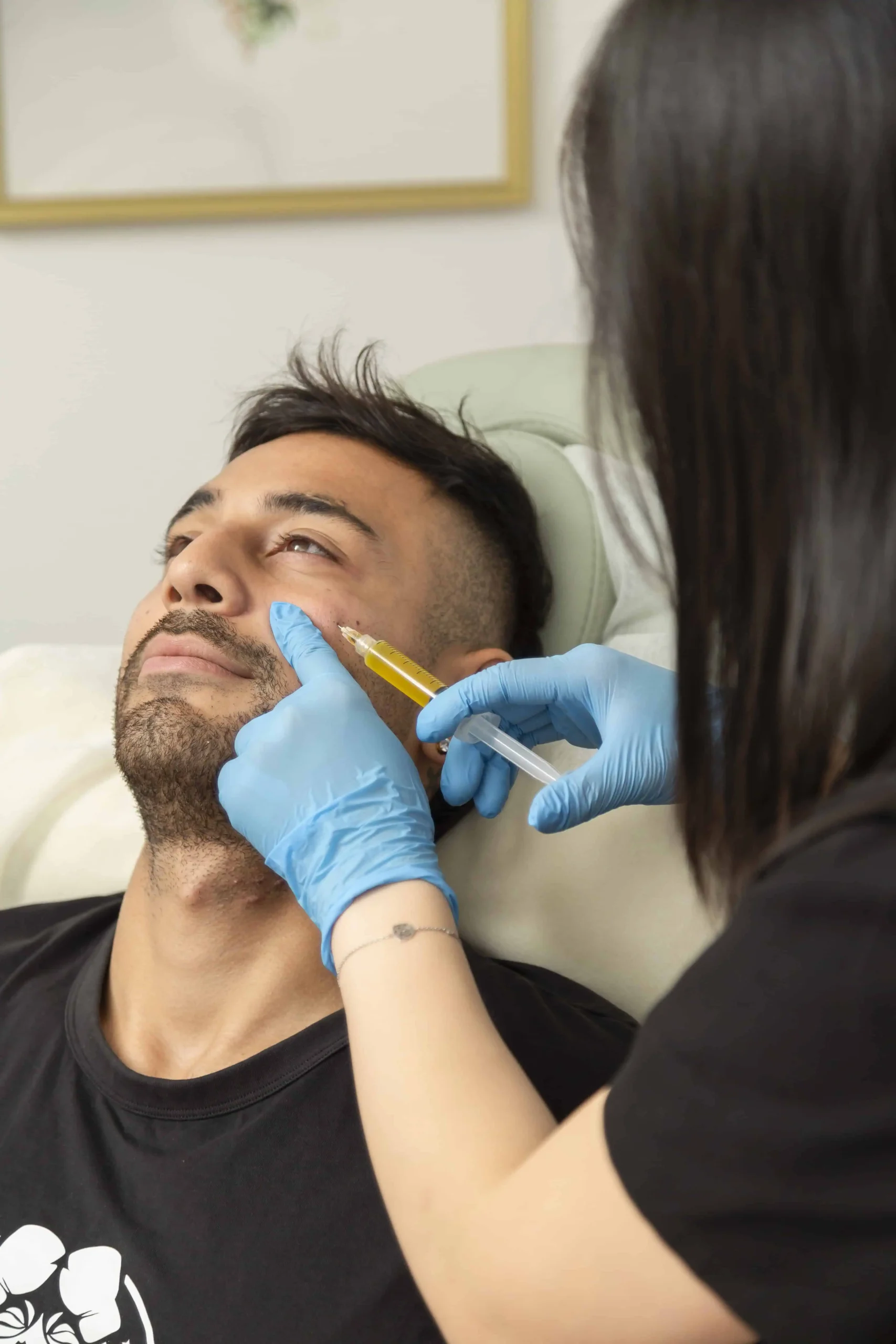 Cosmetic injector treating male patient’s under-eye area for rejuvenation